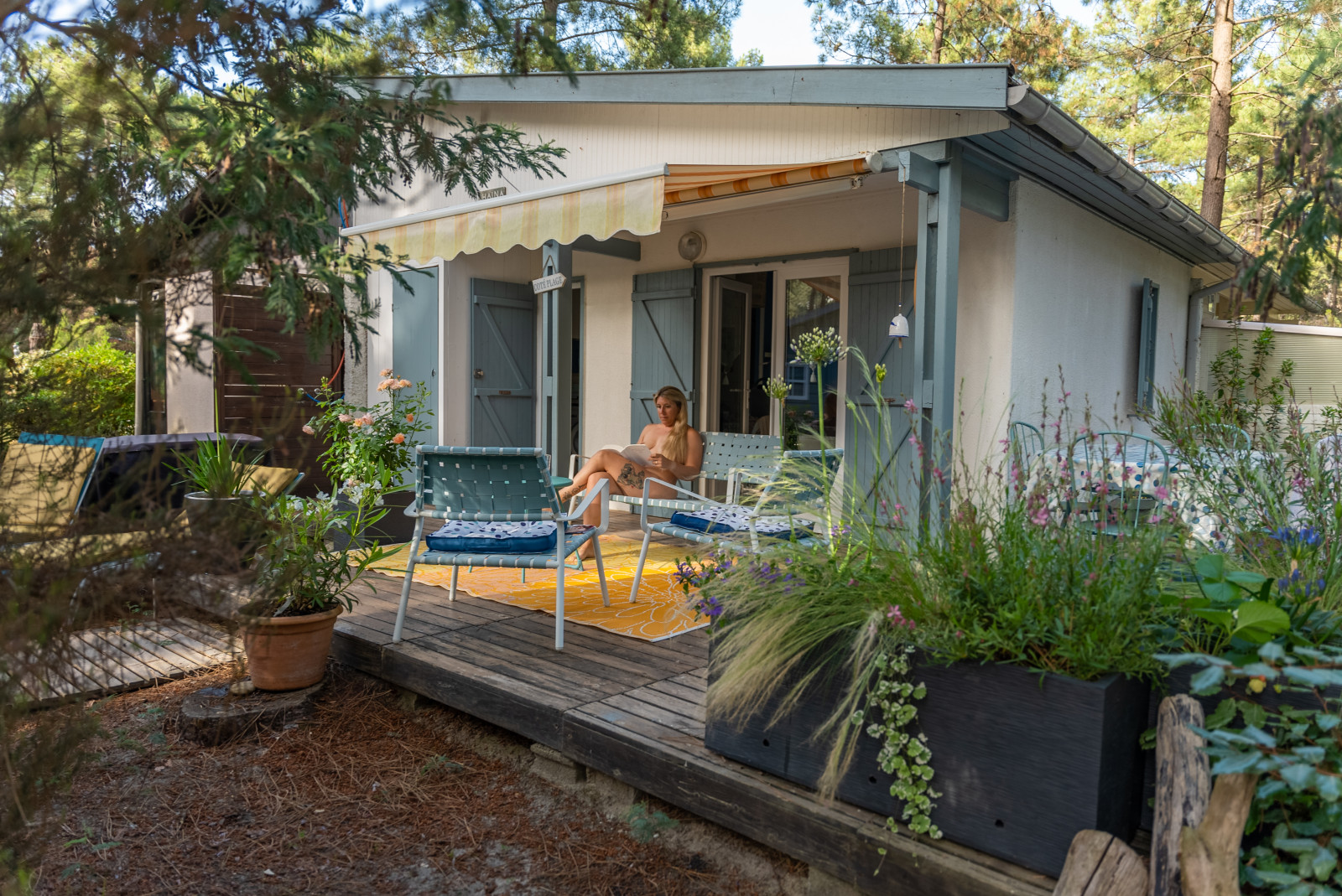 jeune femme naturiste en train de lire sur la terrasse de son chalet